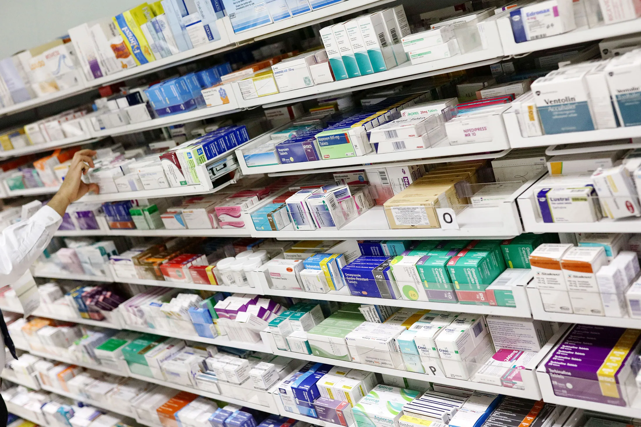 A pharmacist looks for medication on a pharmacy's shelves in London.