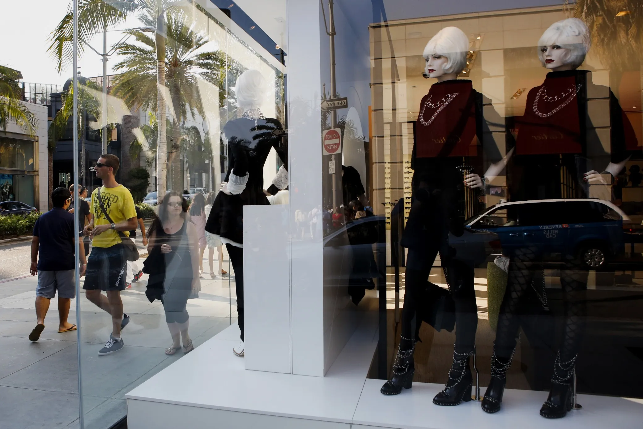 Pedestrians stand in front of mannequin displayed in the window of a store on Rodeo Drive in Beverly Hills, California.