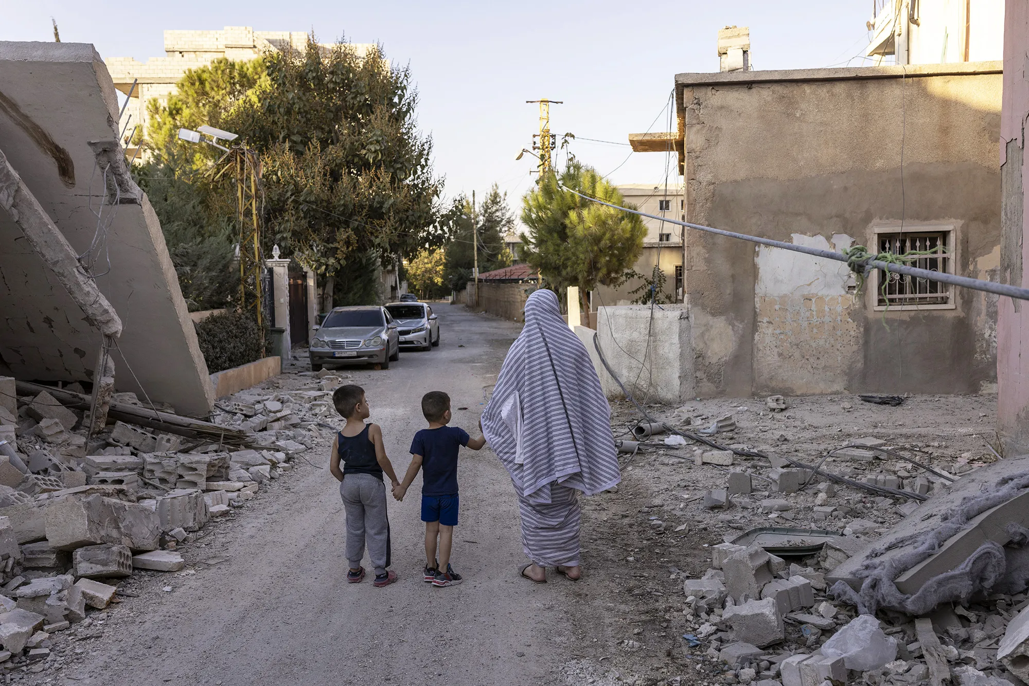 A woman and her two children walk along a street heavily damaged by Israeli air strikes in Baalbek, Lebanon, on Oct. 9.