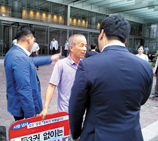 Hwang Sang-ki (center) confronted by Samsung security