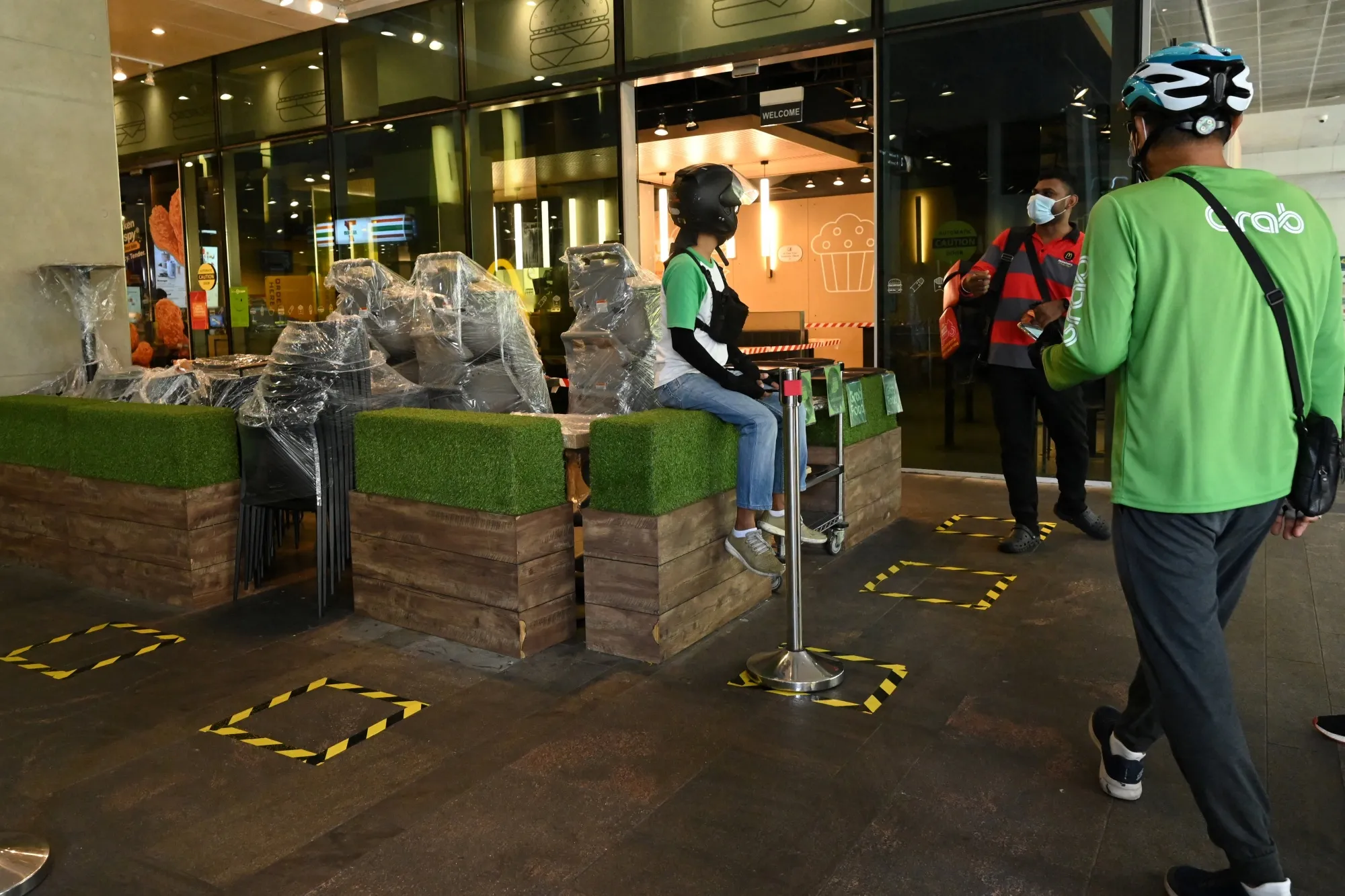 Food delivery workers wait to take orders in front of a fast food restaurant at a shopping mall in Singapore, on July 22.