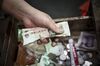 A vendor counts Chinese yuan banknotes in a drawer at a fresh produce market in Shanghai, China.
