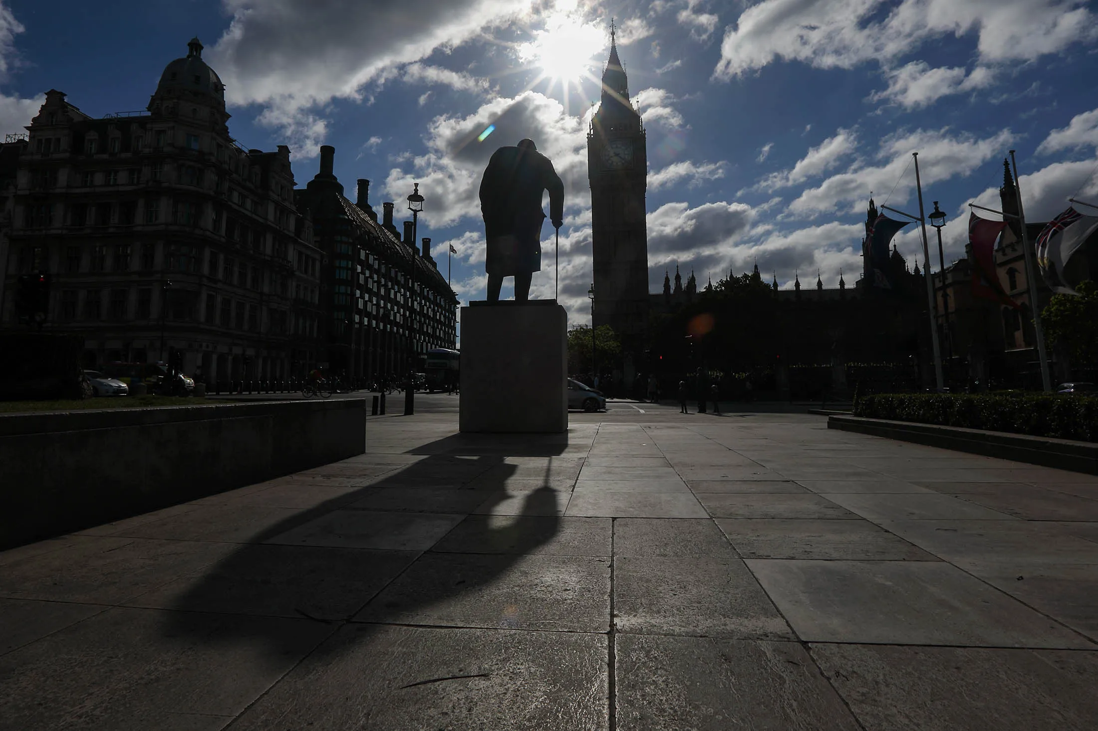 A statue of former Prime Minister Winston Churchill casts a long shadow in front of the Houses of Parliament in London.
