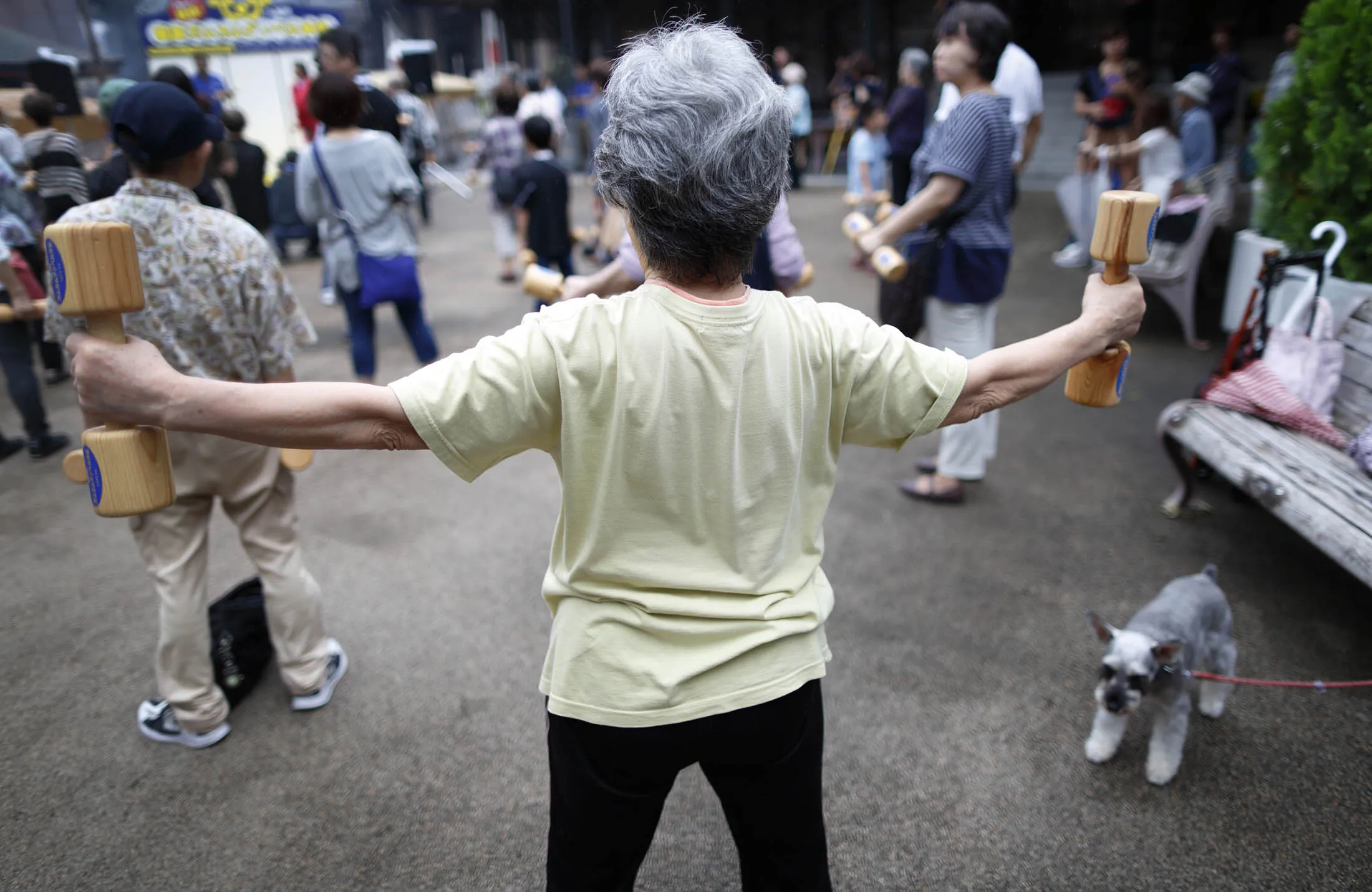A woman exercises with wooden dumbbells at a temple in Tokyo.
