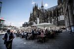 Waiters serve customers on a bar terrace beside Cologne Cathedral in Germany.