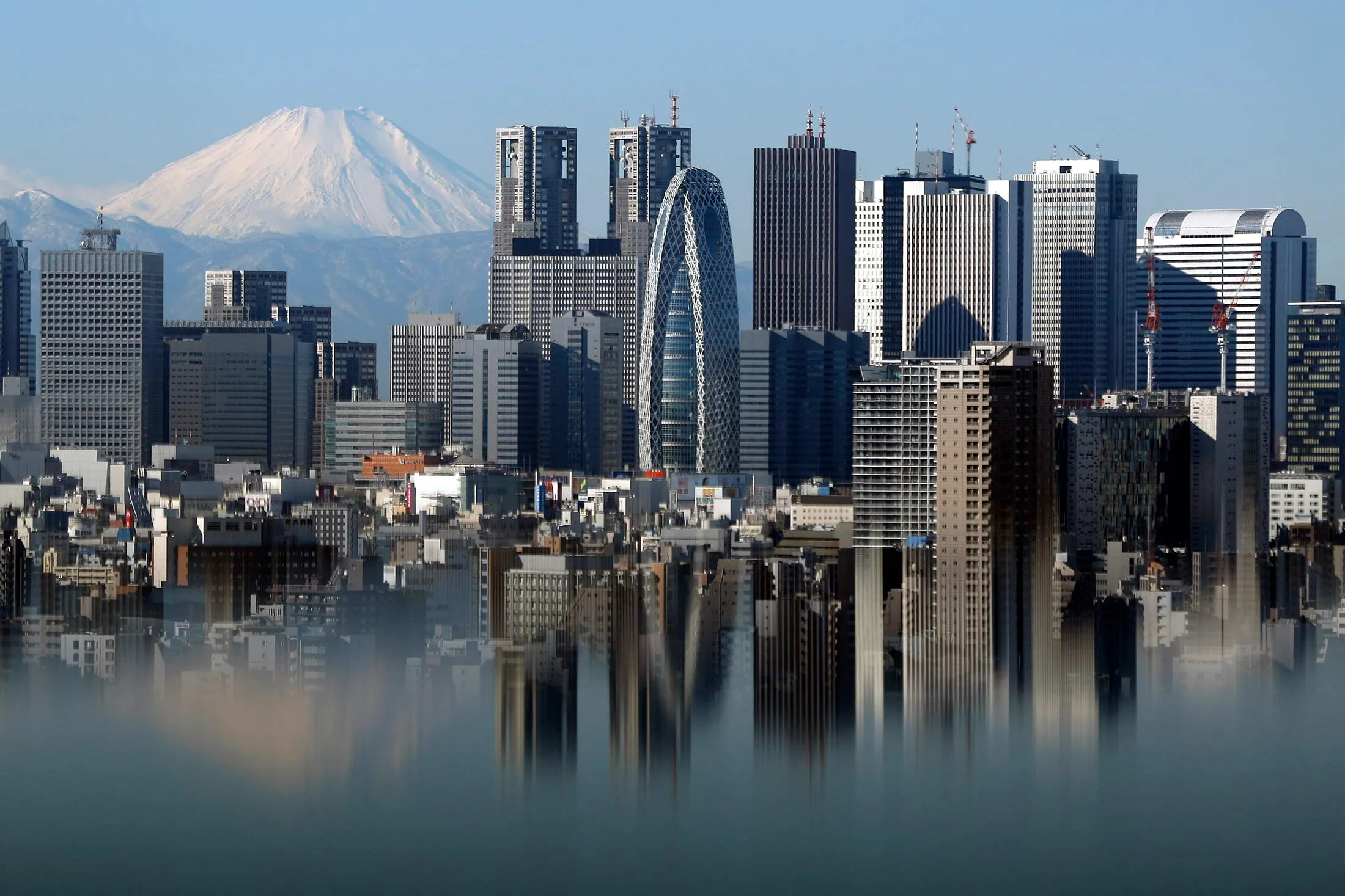 Mount Fuji and buildings in the Shinjuku district are reflected on a table at an observation deck in Tokyo, Japan.
