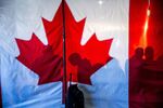Supporters behind the Canada flag during a campaign rally for Pierre Poilievre, leader of Canada's Conservative Party, not pictured, in Oakville, Ontario, Canada, on Sunday, April 27, 2025. Canada goes to the polls on April 28 with Mark Carney's Liberal Party and Pierre Poilievre's Conservatives leading a race dominated by the fallout from US tariffs. Photographer: Ethan Swope/Bloomberg