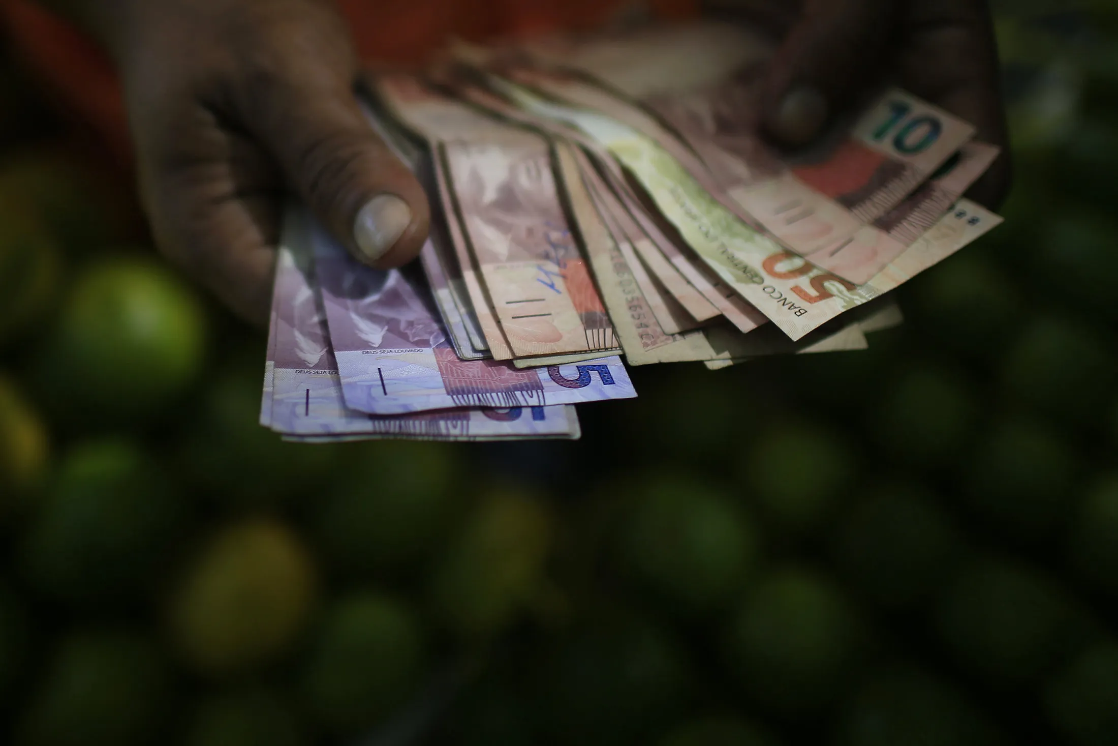 A seller counts real bills at a street market in Botafogo in Rio de Janeiro, Brazil, Tuesday, May 13, 2015.
