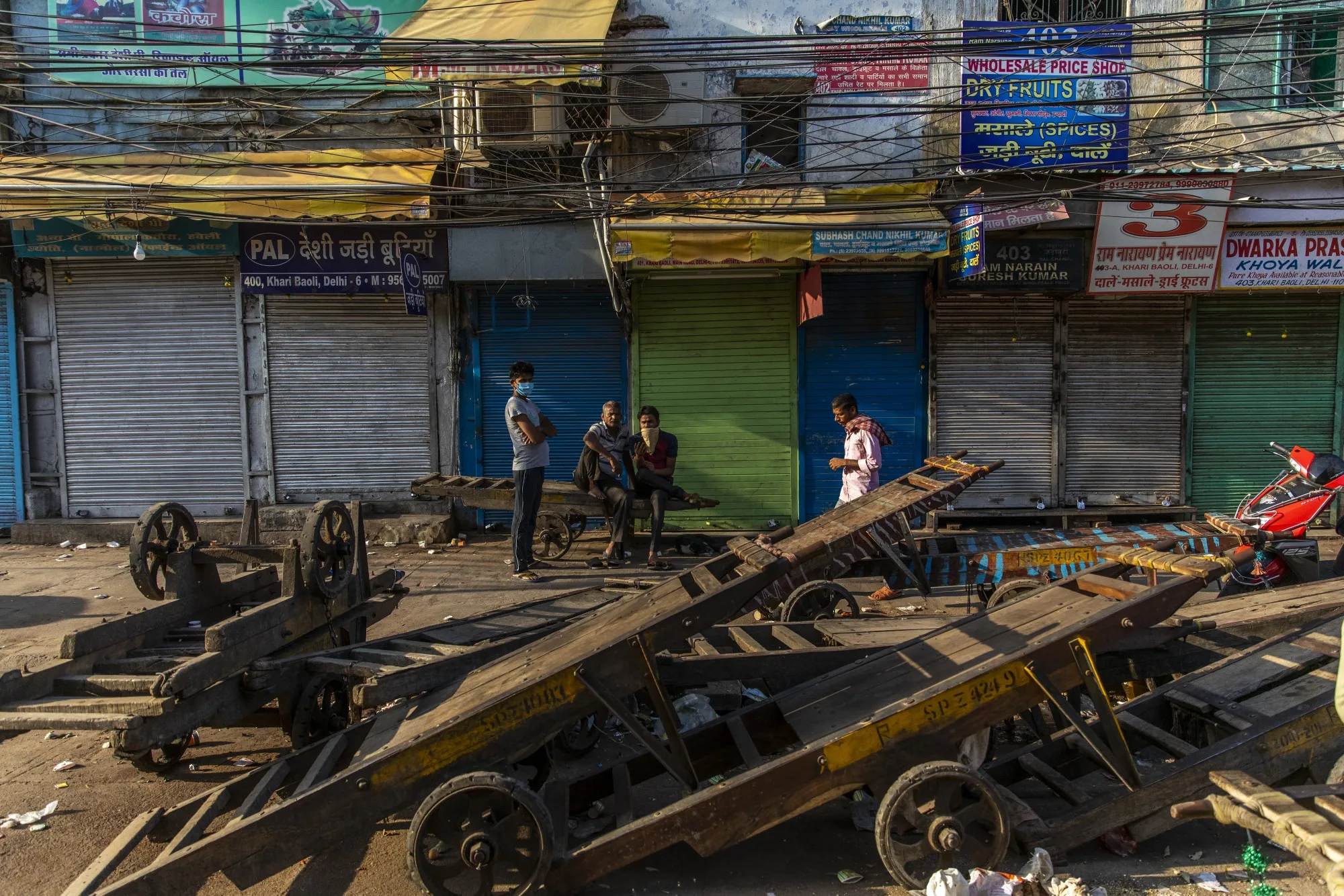 People wearing protective masks stand in front of shuttered stores in Old Delhi on March 22.