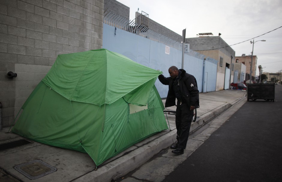An LAPD officer looks in a tent on Skid Row in Los Angeles, California.