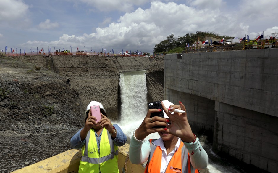 Women take selfies in front of a waterfall during the flooding of the Panama Canal Expansion project.