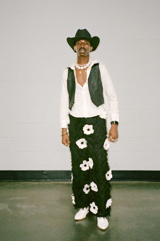 Dwayne Johnson wears a cowboy hat, vest, a large pearl necklace and custom-designed floral pants