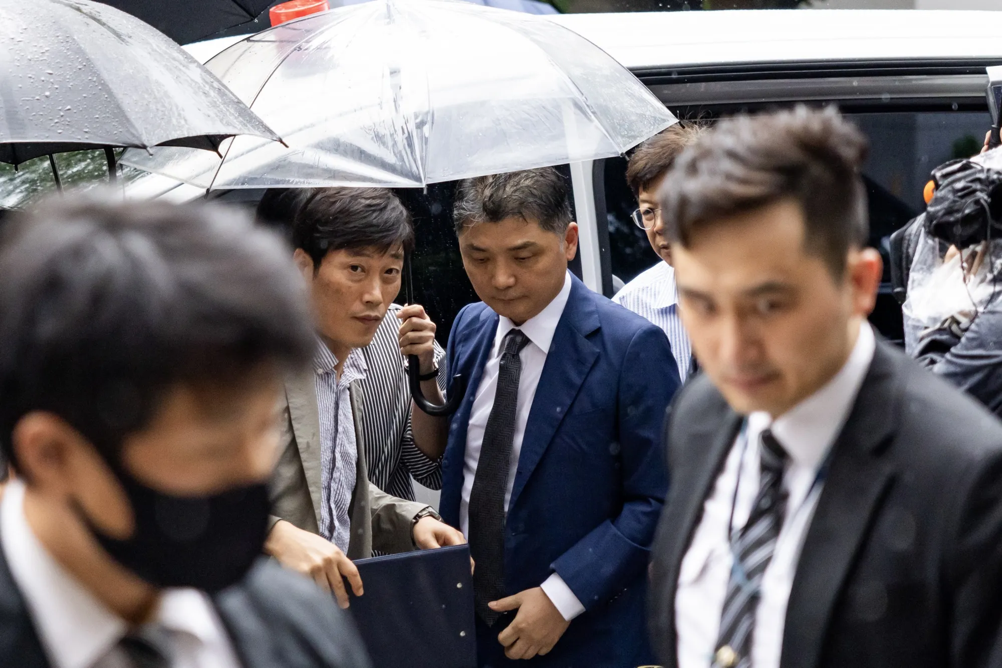 Brian Kim, center right, arrives at the Seoul Southern District Court in Seoul on July 22.