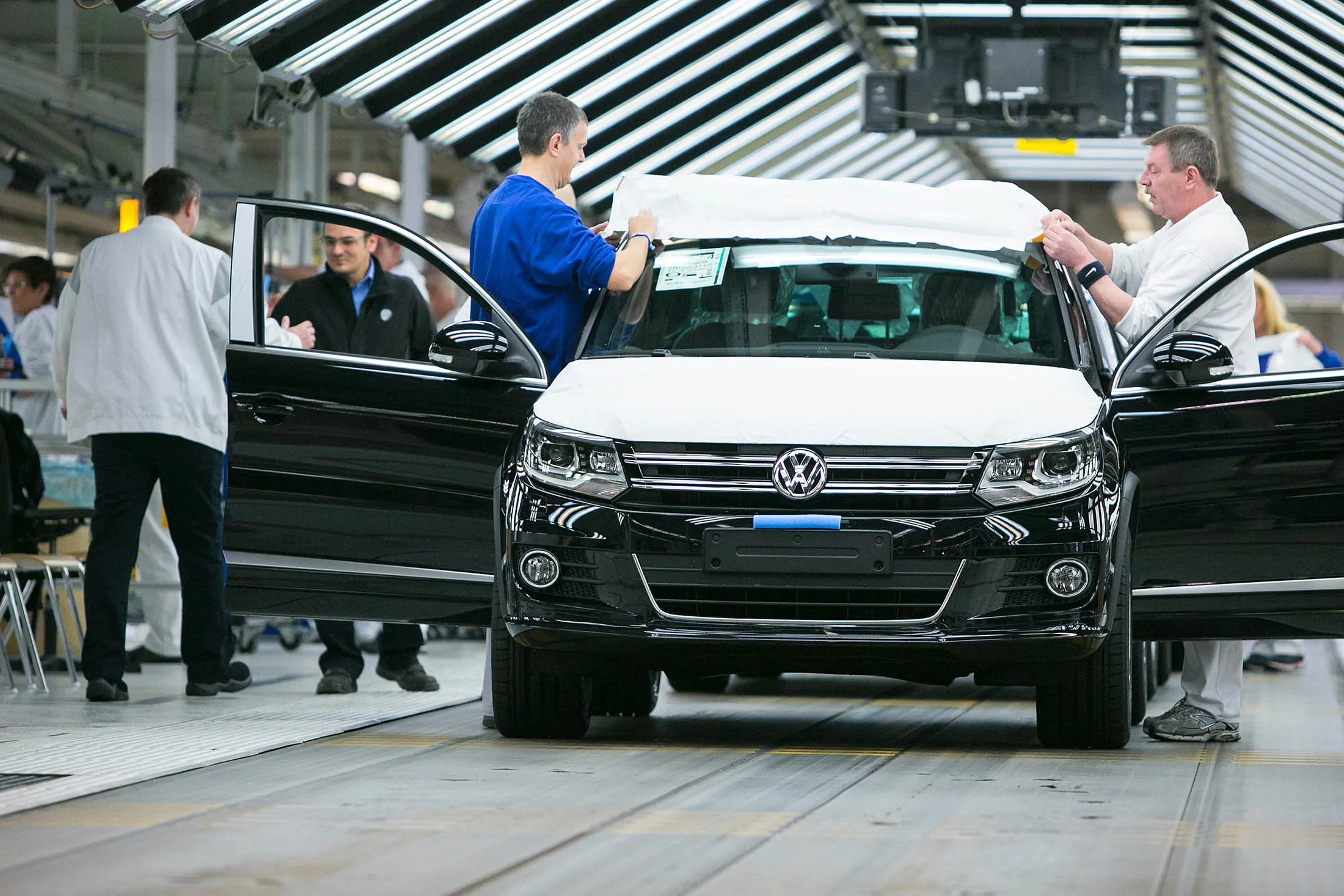Employees secure protective covers to a Volkswagen Tiguan SUV.
