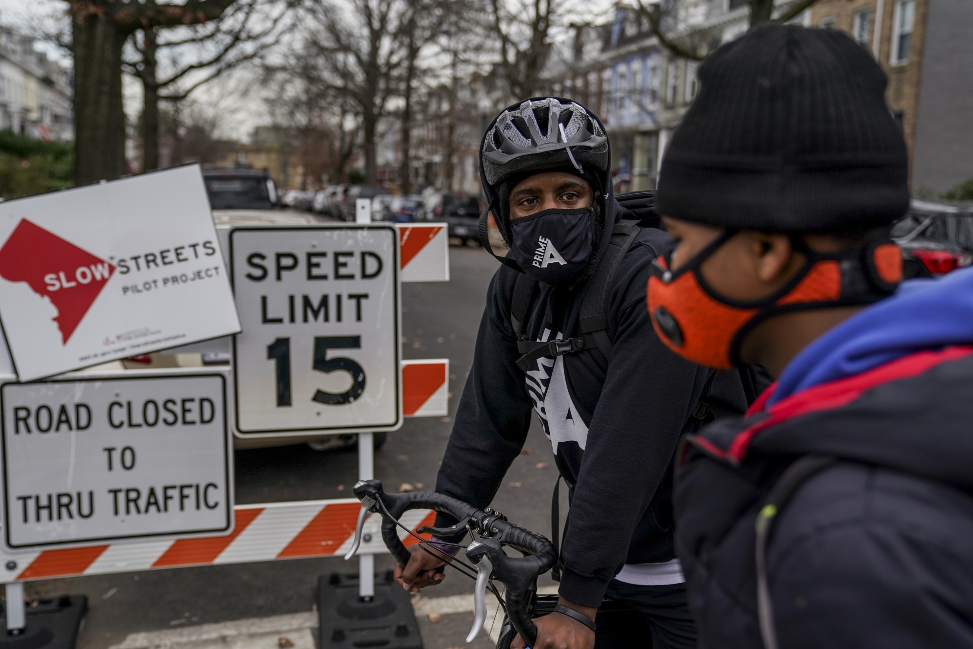 Alex Clark, a teacher at D.C.'s Dunbar High School, talks to student&nbsp;Alex Barry, 18, as he leads a group of students on a bike ride in December. A new D.C. law aims to speed the installation of protected bike lanes across the District.