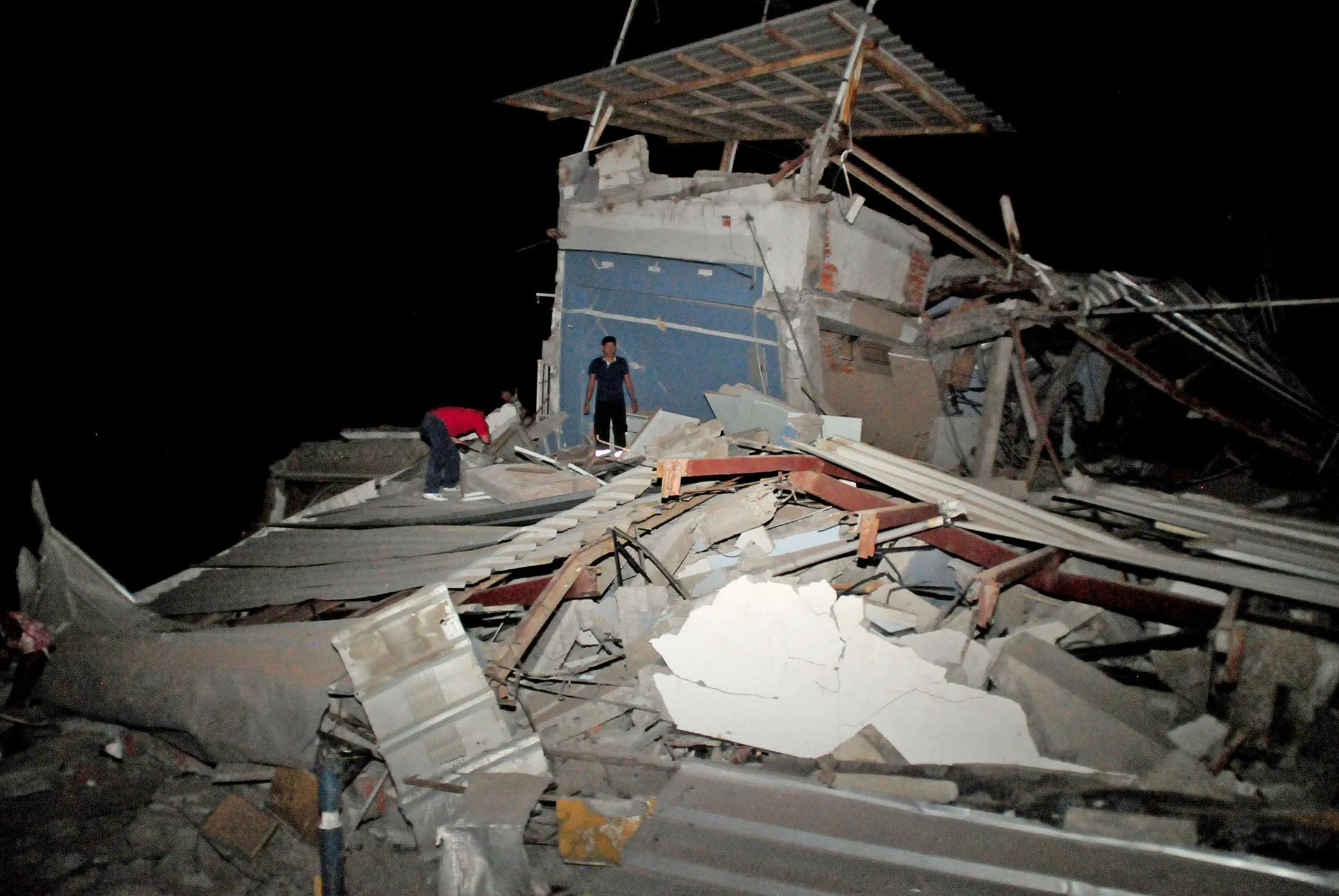 People stand on a destroyed house following an earthquake in Guayaquil, Ecuador on Saturday, April 16, 2016.
