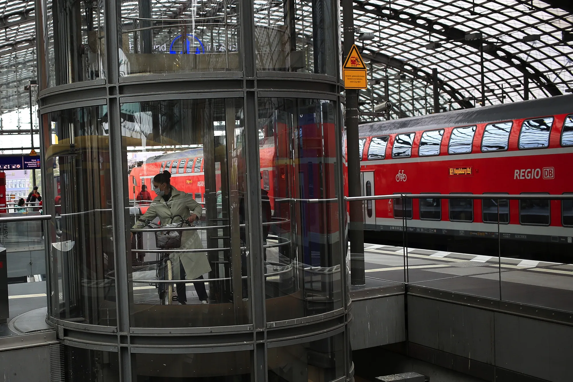 A cyclist stands in a elevator beside a Regio regional train, operated by Deutsche Bahn AG, at Berlin's Central Station railway station in Berlin, Germany, on Monday, May 4, 2020. Germany reported the lowest number of new coronavirus infections and deaths since at least March 30, as the country continues a gradual easing of curbs on public life and allows the economy to slowly restart.