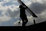 A SolarCity Corp. employee carries a solar panel during an installation at a home in the Eagle Rock neighborhood of Los Angeles, California, U.S.