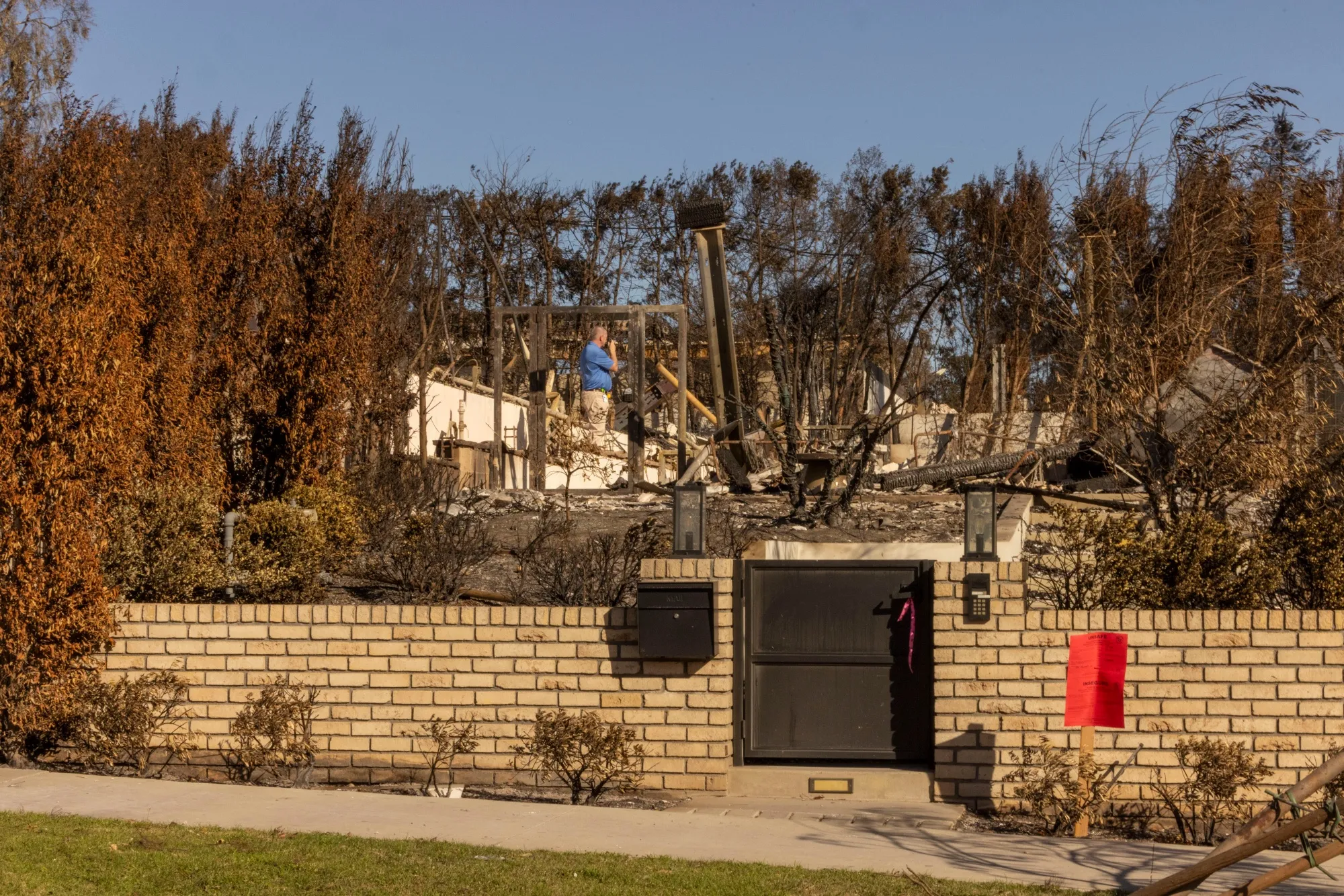 An insurance company employee surveys damage at homes destroyed by the Palisades Fire in the Pacific Palisades area of Los Angeles.