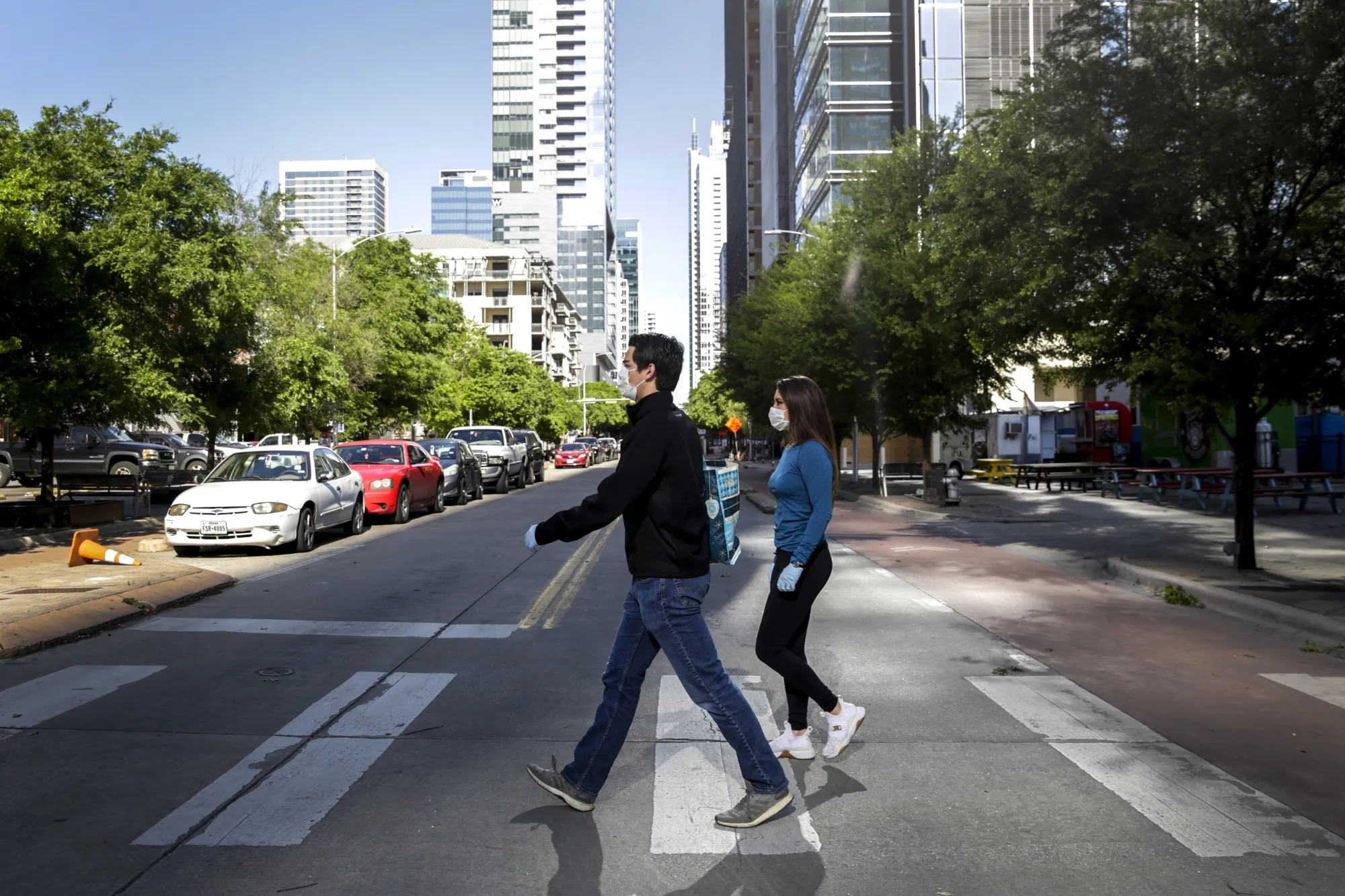 Pedestrians wearing protective masks and gloves cross Congress Avenue in downtown Austin, Texas.