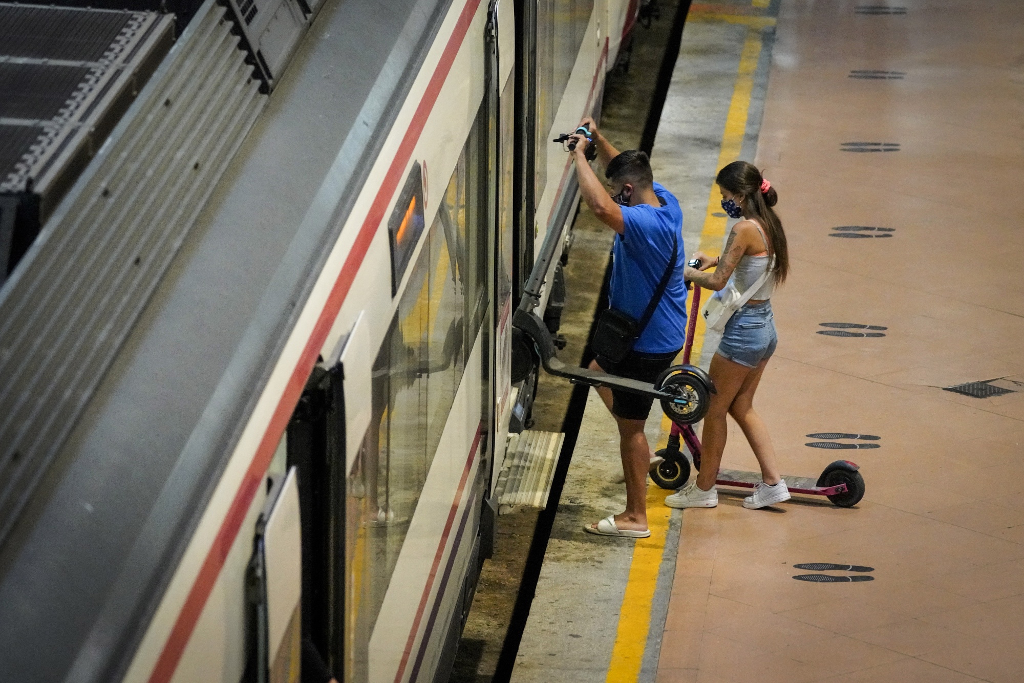 Passengers with electric scooters board a train in Madrid.