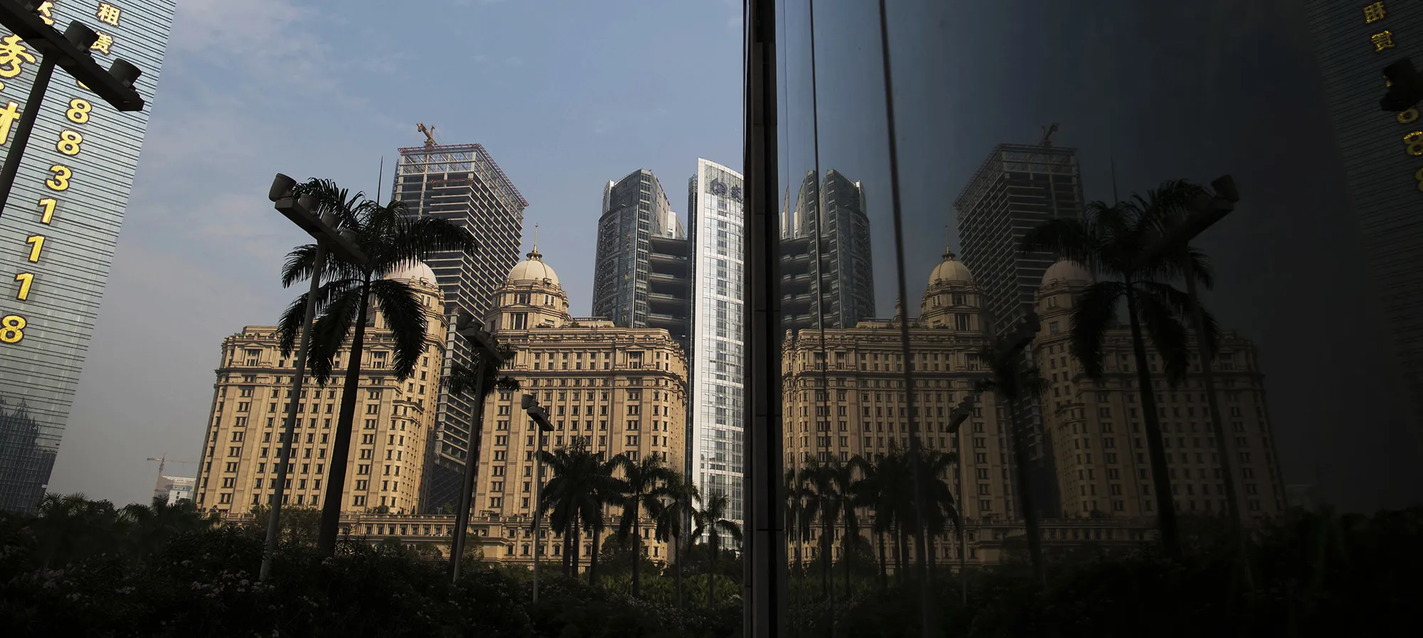 The Agricultural Bank of China Ltd. Guangdong branch, front center, is reflected on a building facade in Guangzhou, Guangdong Province, China.