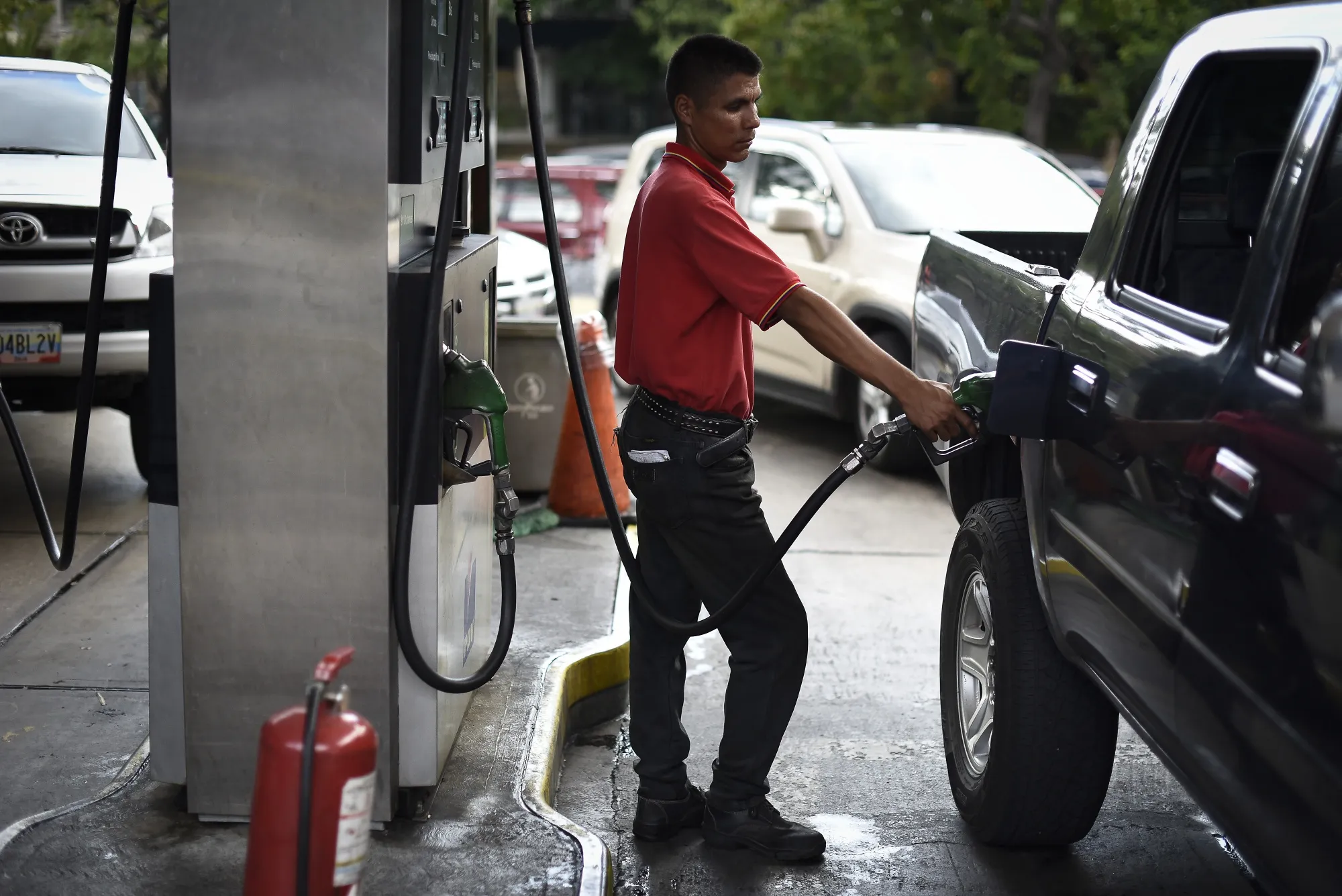An employee refuels a vehicle at a Petroleos de Venezuela SA (PDVSA) gas station in Caracas, Venezuela.