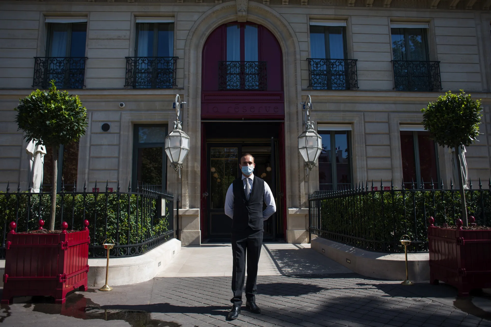 A doorman waits to welcome guests outiside La Reserve, on Aug. 12.