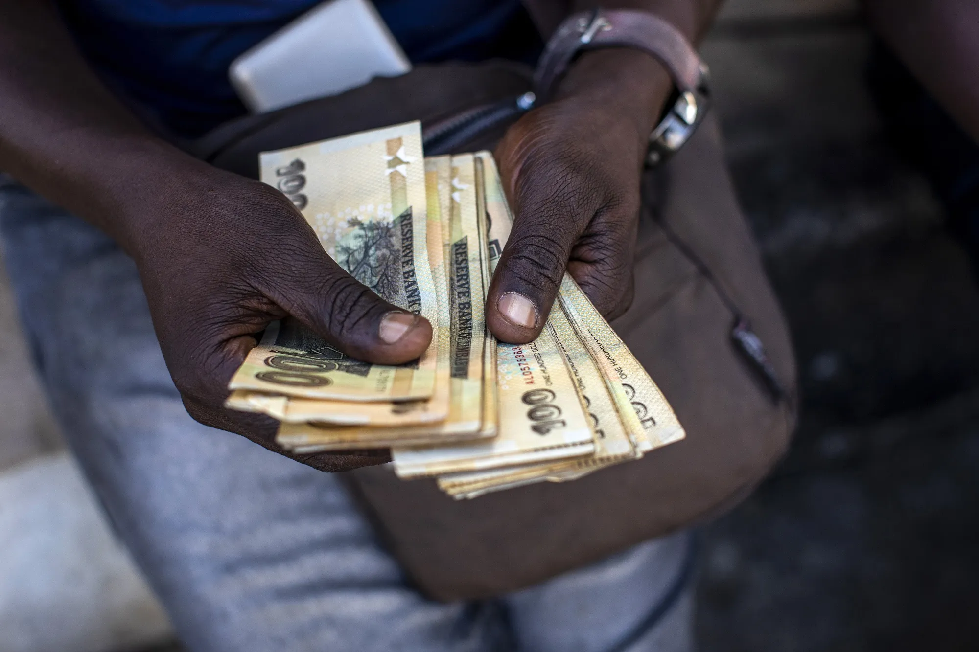 An informal foreign currency exchange trader counts&nbsp;Zimbabwean 100 dollar banknotes in the central business district of Harare, Zimbabwe.