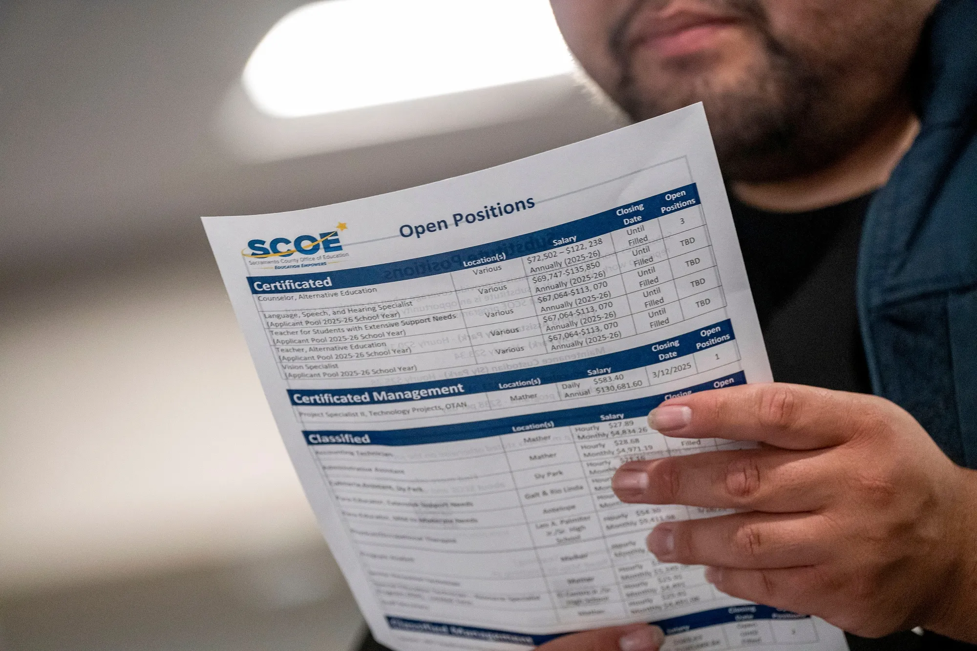 An attendee holds a flyer listing open positions at a City Career Fair hiring event in Sacramento, California.