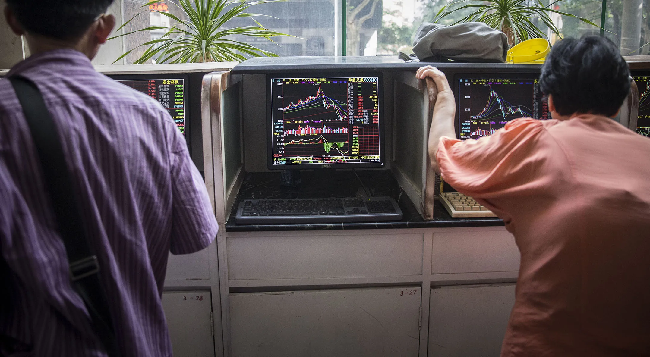 Investors stand at trading terminals at a securities exchange house in Shanghai.
