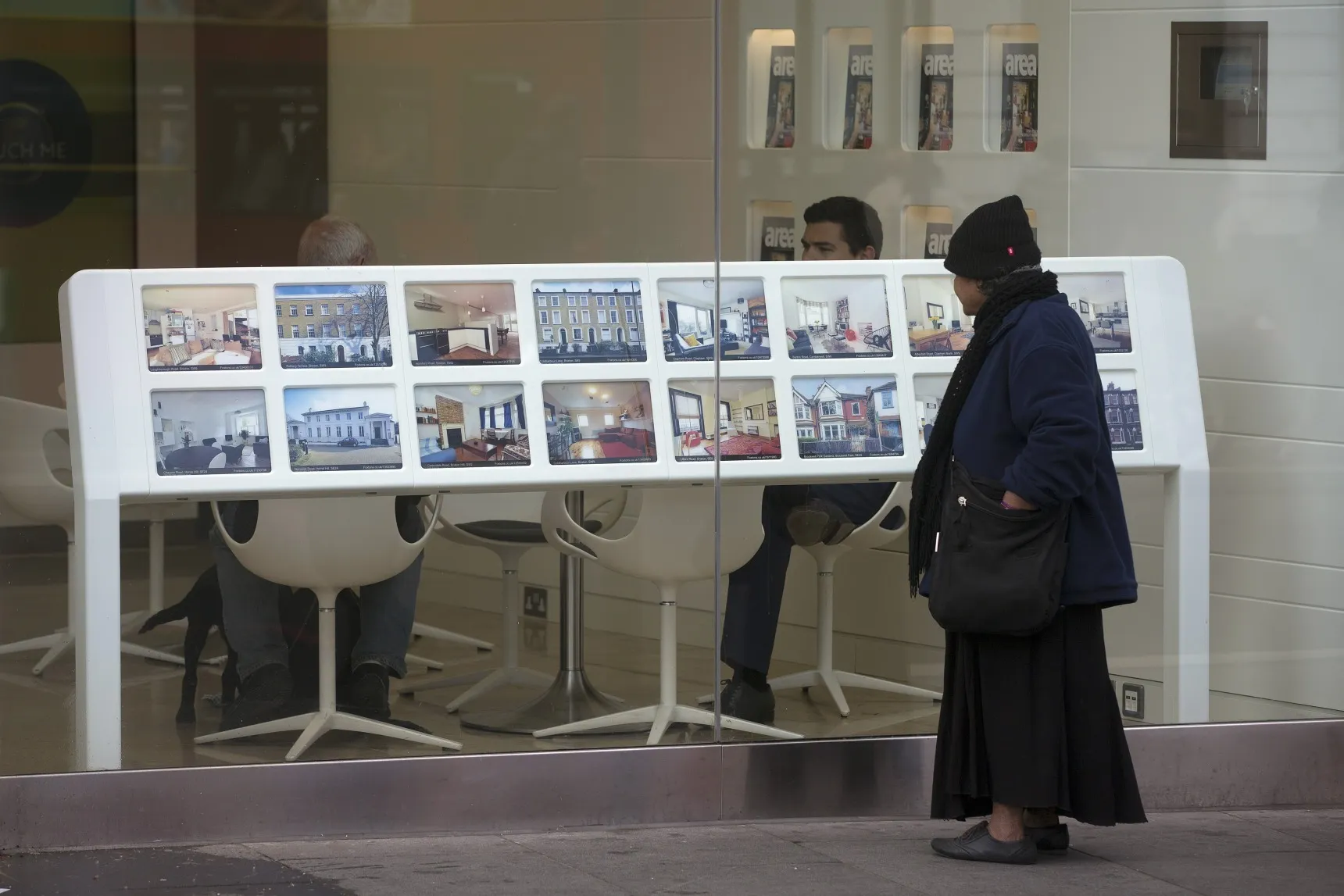 A pedestrian looks at properties displayed for sale in the window of a Foxtons estate agents store in the Brixton district of London, U.K.
