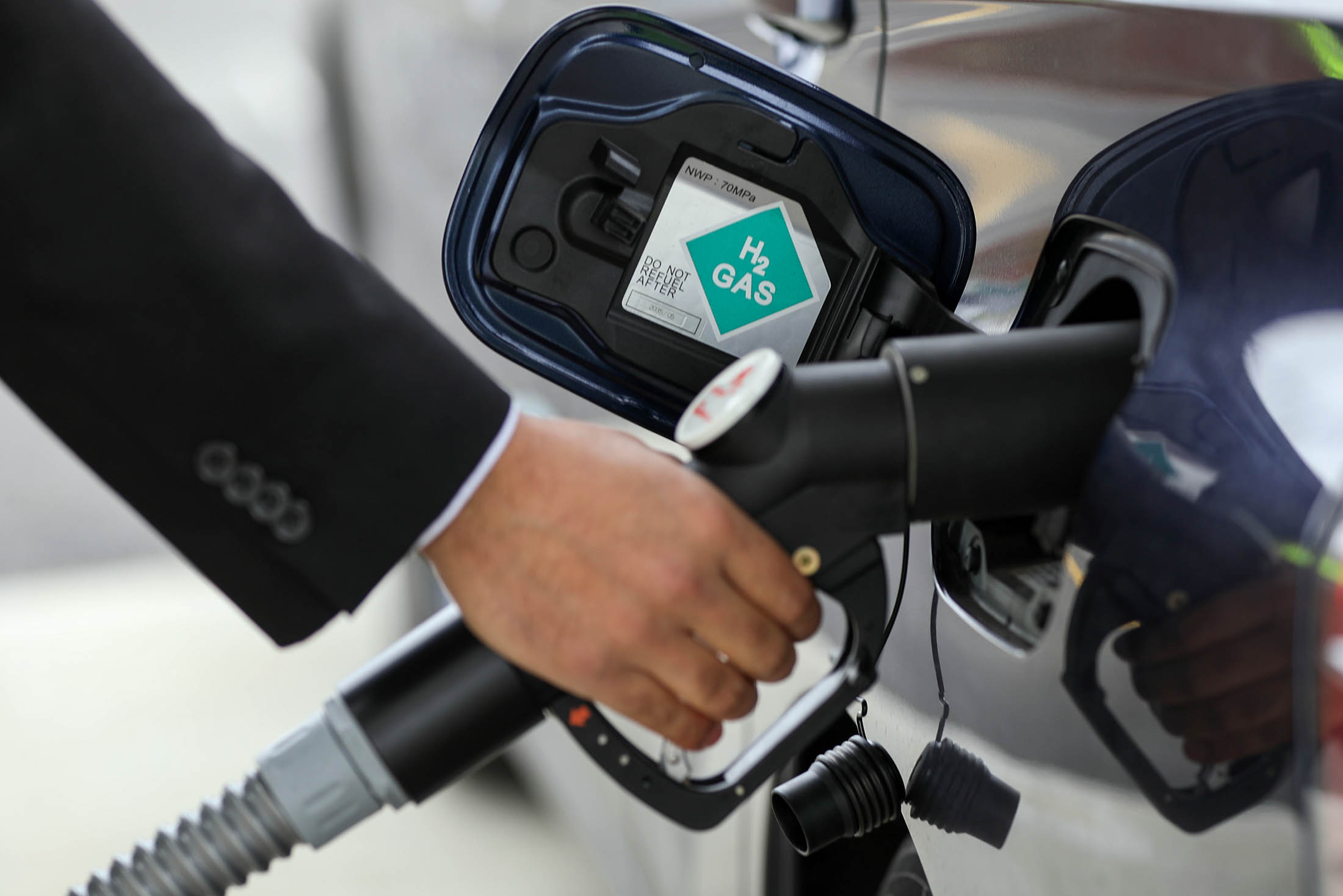 A driver places a hydrogen fuel pump into a Mirai hydrogen fuel powered automobile, manufactured by Toyota Motor Corp.