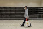 A customer wearing a protective mask walks past the empty shelves of the toilet paper and tissues section of a supermarket in Hong Kong, Feb. 6.