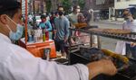 A worker grills meat and vegetables as customers wait in line to order take-out at a restaurant in New York on June 20.