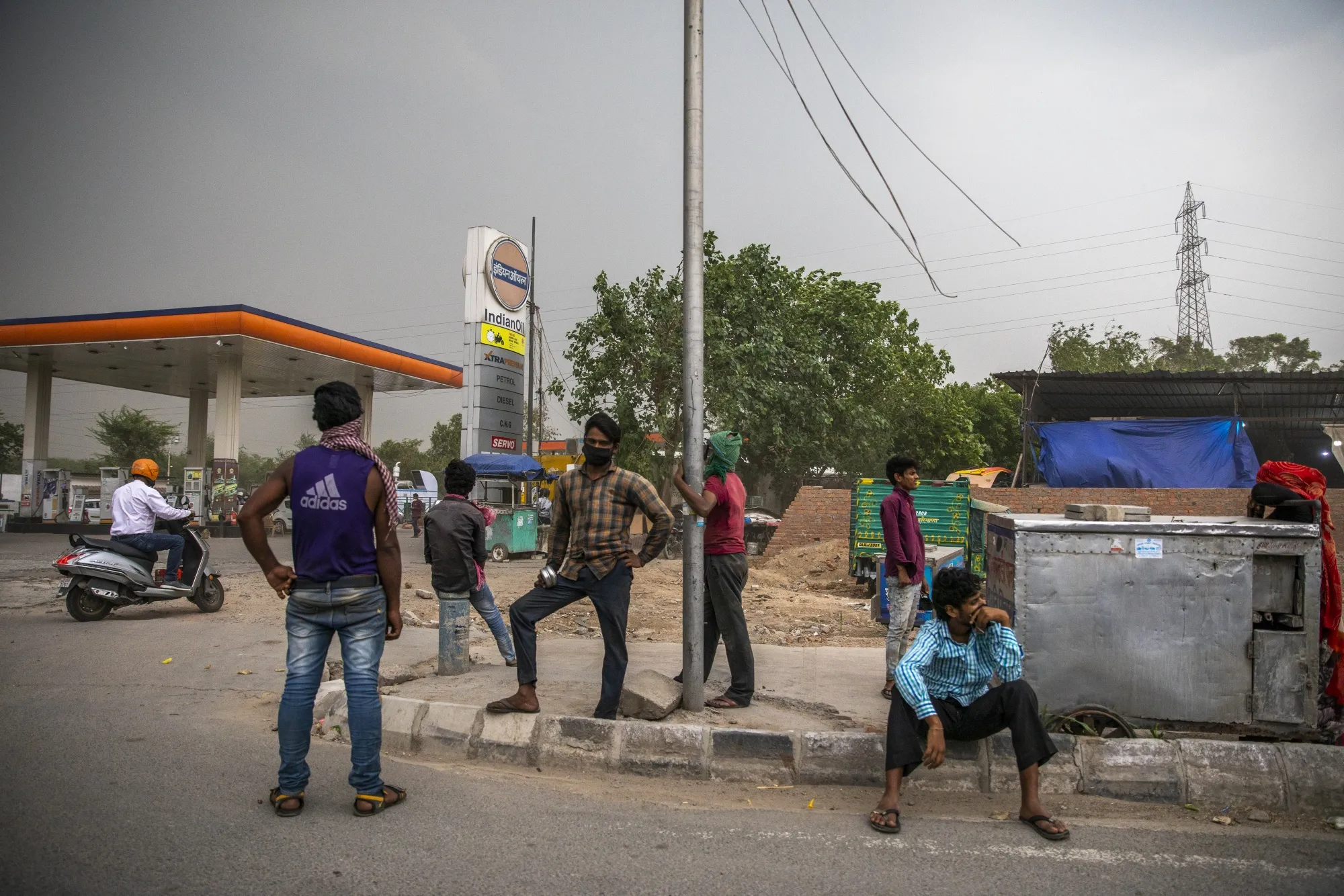 People with and without protective masks stand next to a gas station during a partial lockdown&nbsp;in New Delhi, India, on&nbsp;May 14.