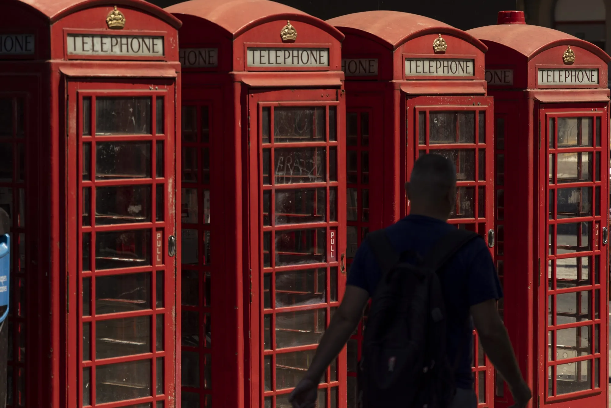 A row of red telephone boxes in London.