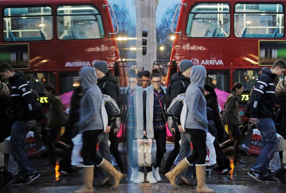 Shoppers reflected in a store window on London's Oxford Street.
