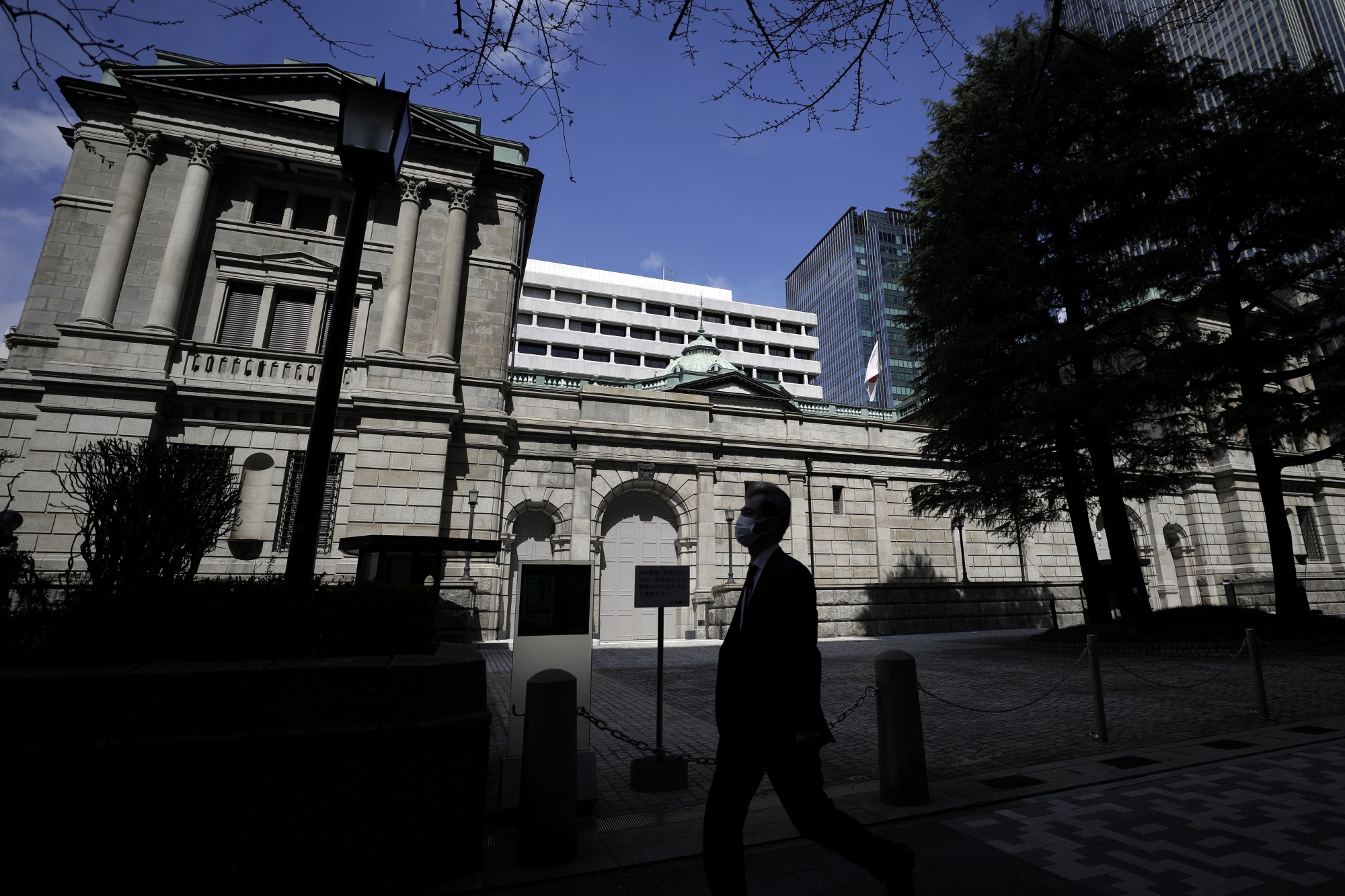 A pedestrian wearing a protective mask walks past the Bank of Japan&nbsp;headquarters in Tokyo, Japan.