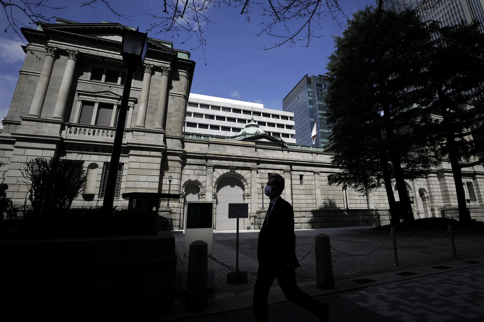 A pedestrian wearing a protective mask walks past the Bank of Japan&nbsp;headquarters in Tokyo, Japan.