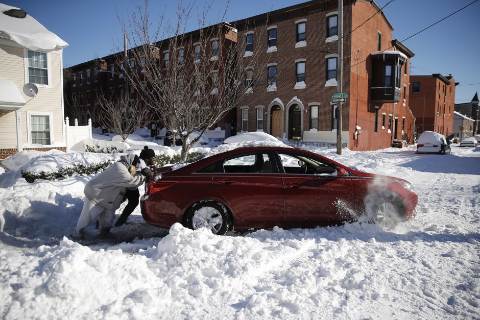 A family tries to push out a snow-bound car after a winter storm on January 24, 2016, in Philadelphia.