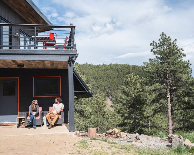 Ward-Karet and O'Malley sit in front of their cabin under an awning at their 35-acre property in Fourmile Canyon, near Boulder.