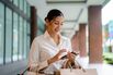 Asian woman with shopping bags using a smartphone while walking in the city