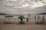 A vendor takes down umbrellas at the end of the day at Patong Beach in Phuket, Thailand.