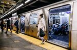 Passengers wearing protective masks ride the L subway train in New York.