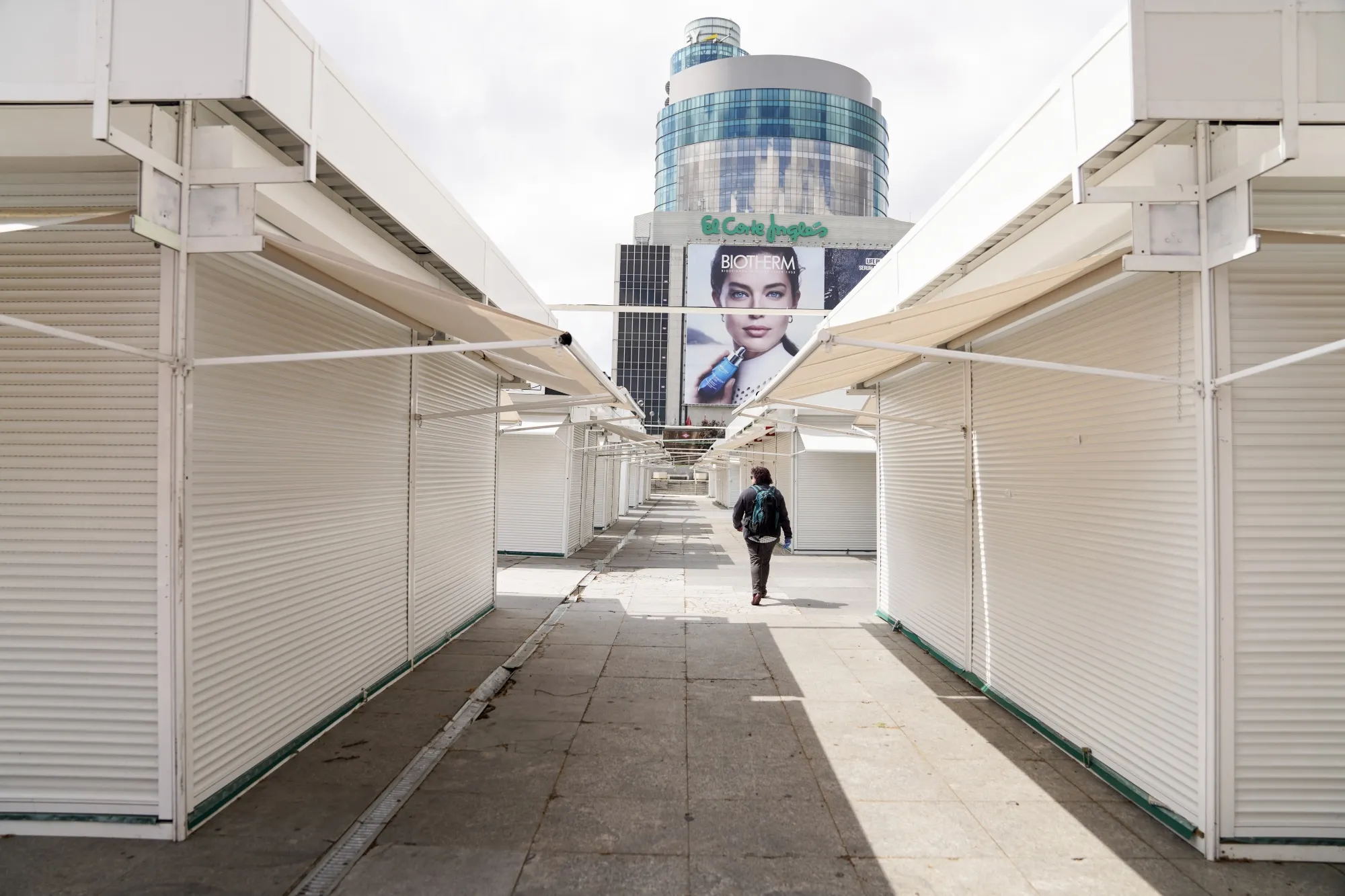A pedestrian walks by closed outdoor retail huts in Madrid on April 13.