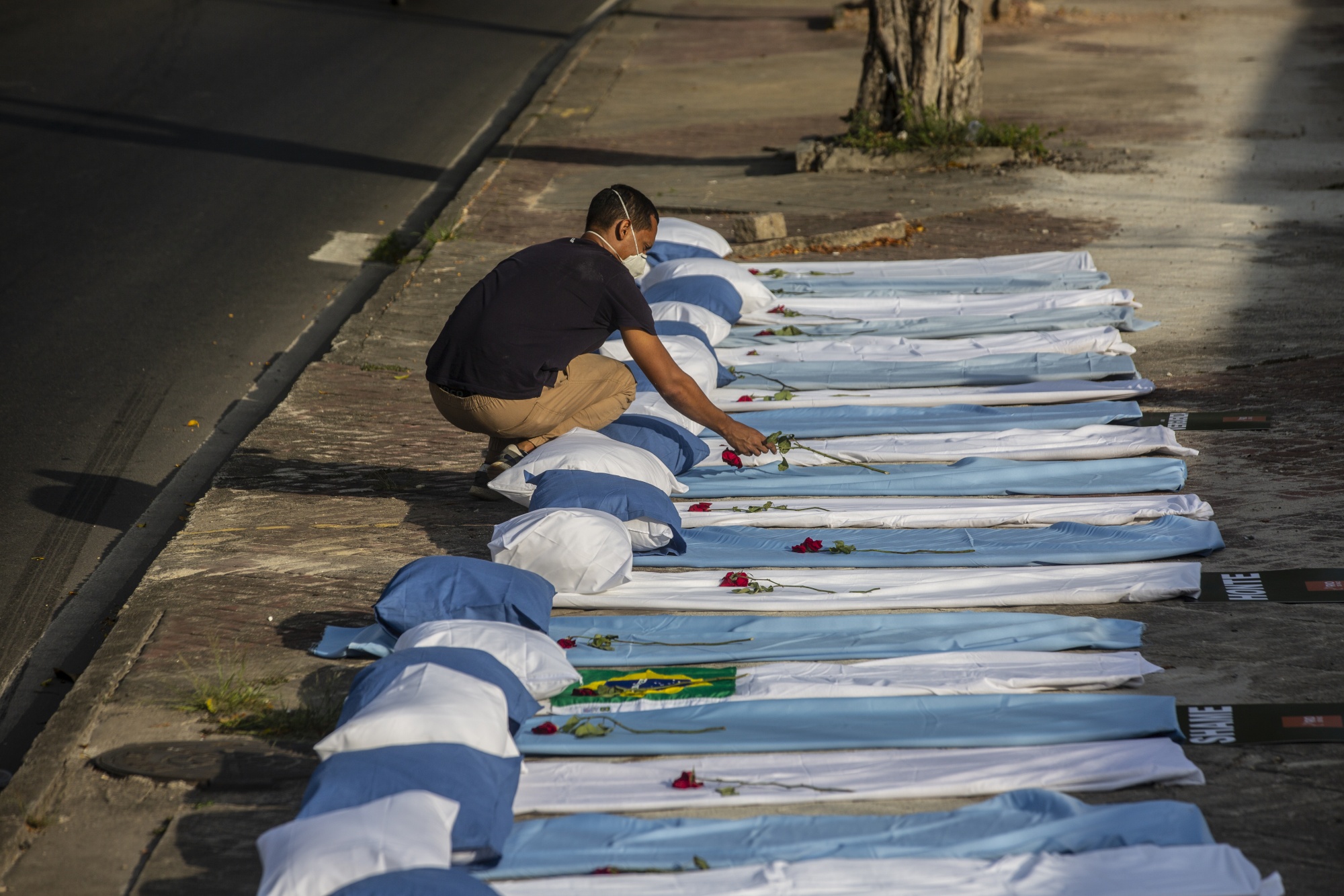 A demonstrator places a rose on a blanket during a protest against the government’s pandemic response, outside of the Raul Gazzola hospital in Rio de Janeiro on March 24.