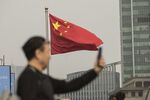 A Chinese national flag flies as a man uses a smartphone in Shanghai, China.