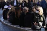 Tourists wearing protective face masks sit at Spain square fountain in Rome, Italy on Feb. 25.