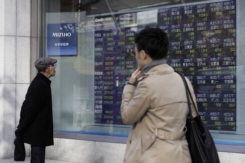 株価ボード前の歩行者